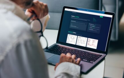 A professional focuses on analyzing detailed business reports displayed on a laptop screen. The graphics include various charts and performance metrics, highlighting statistical trends for comprehensive decision-making in a corporate environment.